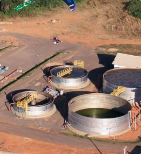 Estação de tratamento de esgoto em aço inox vista do alto, com tanques redondos e passarela amarela